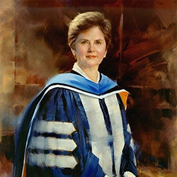 commissioned portrait of short-haired woman, hands crossed over one another, in academic dress. 