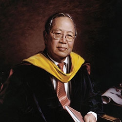commissioned portrait of man in black and yellow academic regalia sitting down